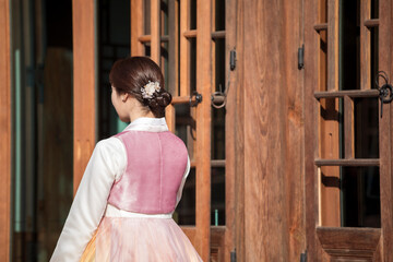 Obraz premium Rear view of woman in Hanbok standing at traditional Korean house