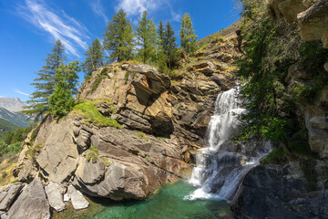 Fototapeta na wymiar une cascade en montagne avec son eau verte et des sapins