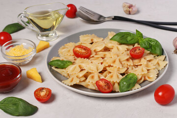 Farfalle pasta with cherry tomatoes, tomato sauce and basil on white background, close up