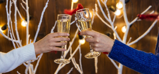 Christmas glasses of champagne in woman's hands on garland lights illumination unfocused bokeh