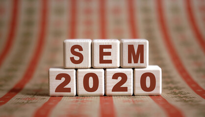 SEM 2020 text on wooden cubes on a monochrome background with reflection.