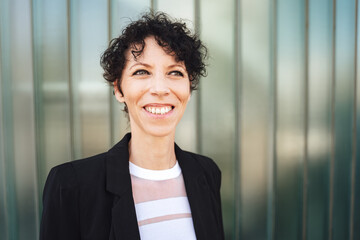 Close up portrait of smiling Caucasian businesswoman looking away while standing against green wall
