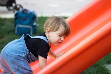 Fototapeta na wymiar a baby trying hard to climb the slide in a park 