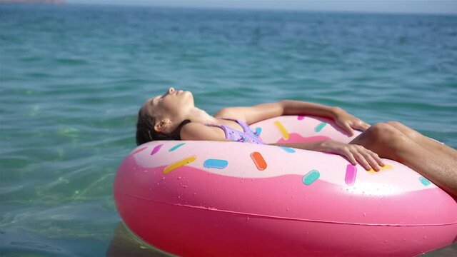 Adorable girl on inflatable air mattress in the sea