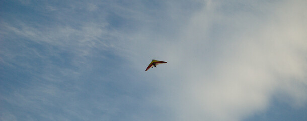 Asa delta com motor em céu aberto com cores amarelo e vermelho