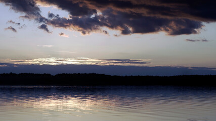 Fototapeta na wymiar Summer sunset over the lake, dark clouds on the horizon. 