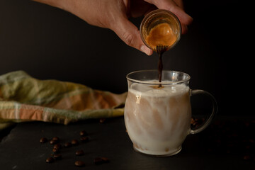 Espresso coffee poured on foamy milk with dark background