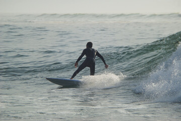 Surfista a fazer surf numa onda no mar ao por do sol