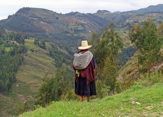 Fototapeta na wymiar Indigenous quechua woman looking at the horizon in the Andes mountain range, Cajamarca, Peru.