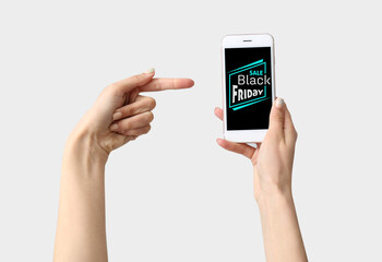 Female hands with mobile phone on light background. Black Friday sale