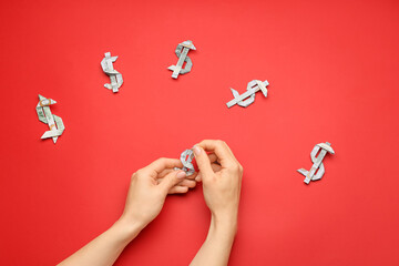 Woman making origami figures from dollar banknotes on color background