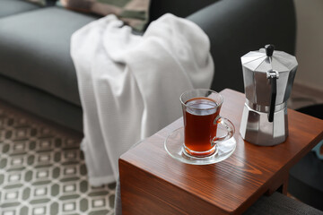 Cup of drink and coffee pot on armrest table in room