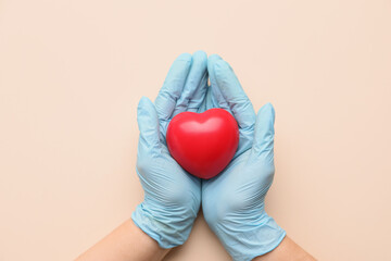 Hands of doctor with heart on color background. Cardiology concept