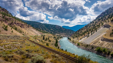 Fototapeta na wymiar Railway and the Trans Canada Highway follow the Thompson River with its many rapids flowing through the Canyon in the Coastal Mountain Ranges of British Columbia, Canada