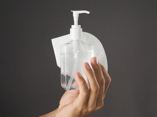 Close-up. Hand holding sanitizer bottle and protective face mask KN95. Gray background.