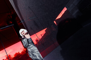 Stylish futuristic blonde in cyberpunk style on a red mirror background.