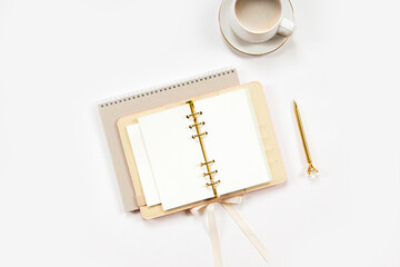 Notepad and beige leather covered diary with clean sheets, gold pen, cup of flat white coffee