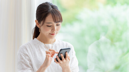 リビングでスマートフォンを使う女性 © taka