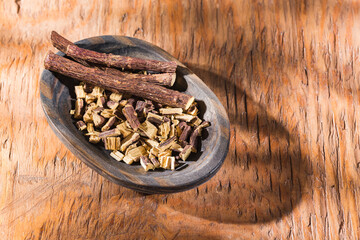 Licorice root in bowl on wooden background