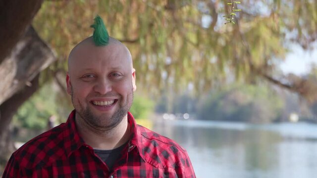 An alternative man with a green mohawk looking at camera and smiling