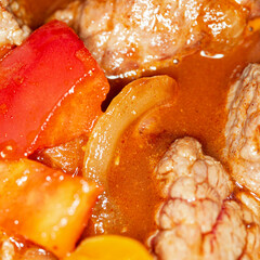 Hungarian goulash. Slices of beef stewed with onions, sweet pepper, tomatoes with oil and spices, macro picture. 