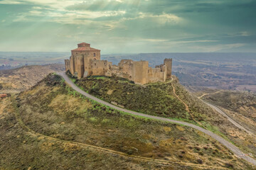 Sunrays shining through the clouds at historic Montearagon castle near Huesca Spain with partially restored walls and towers