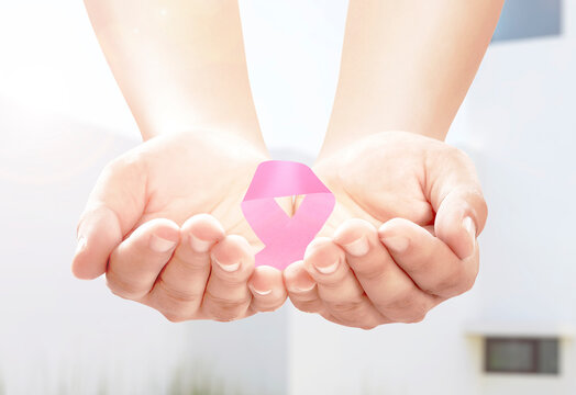 Human hands showing pink awareness ribbon