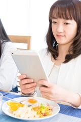 Obraz na płótnie Canvas タブレットPCを見ながら食事する女性