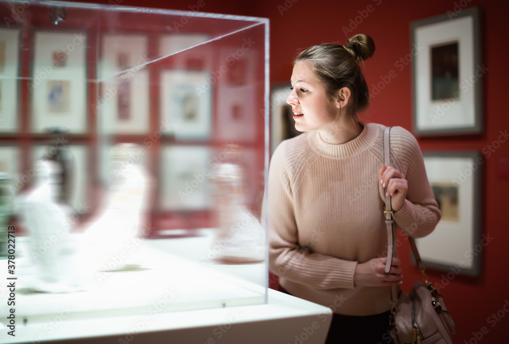 Wall mural young happy positive female visitor looking at exhibition in museum of ancient sculpture