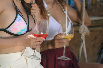 Girls drinking cocktails on beach in bikinis