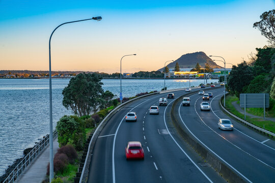 Cars in long exposure  blurred in motion travelling along Takitimu Drive with landmak Mount Maunganui in distance at sunrise.