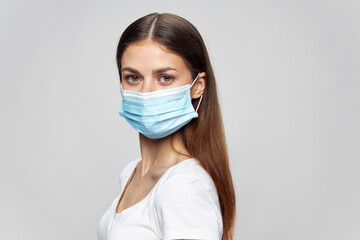 Woman in a white T-shirt and in a medical mask on an isolated background portrait