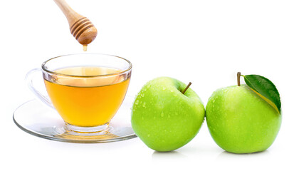 Closeup cup glass of apple cider tea with honey and fresh ripe granny smith green apples fruit isolated on white background. 
