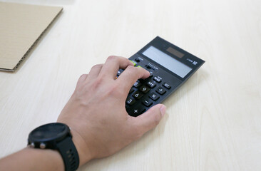 Hand pushing button of the calculator on the meeting table for calculate cost with copy space concept. Body part