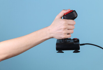 Hands holding retro joystick on blue background. Old gaming. 80s retro wave © splitov27