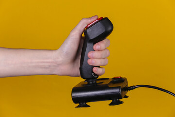 Hands holding retro joystick on yellow background. Old gaming. 80s retro wave © splitov27