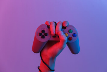 Hands holding retro joystick in blue-red neon gradient light. Old gaming. 80s retro wave. Minimalism