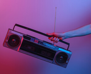 Hand holding retro radio tape recorder. in blue-red neon gradient light. Pop culture. 80s retro wave