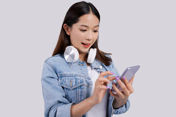 Smiling Asian woman using an application to listen to music on her phone. She wears bluetooth headphones.