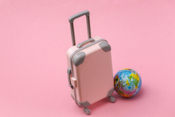 International travel concept. Mini plastic travel suitcase on pink pastel  background. Minimal style