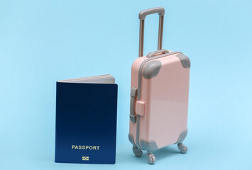 Travel or trip concept. Mini plastic travel suitcase with passport on blue background. Minimal style