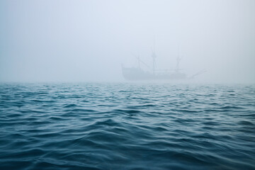 Obraz premium Fog over the sea waves, and misty ship on a background