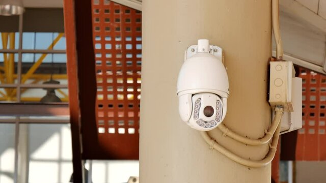 Security video camera moving to scan the area for surveillance purposes. Motorized CCTV recording technology.