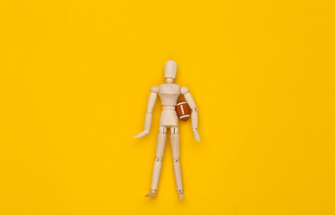 Mini wooden puppet holding rugby ball on a yellow background