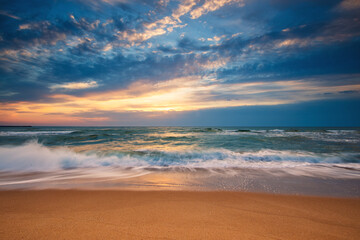 Beach sunrise over the sea and dramatic clouds