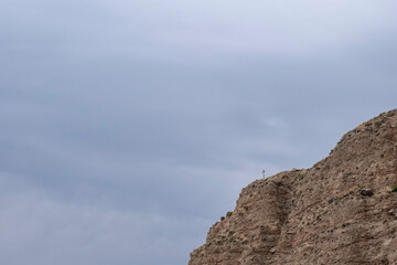 Christian cross on mountain cliff. Religion recluse concept. Reclusion life concept.