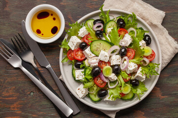 Greek salad of fresh cucumber, tomato, sweet pepper, lettuce, red onion, feta cheese and olives with olive oil. Healthy food, top view