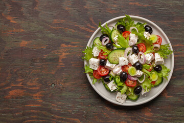 Greek salad of fresh cucumber, tomato, sweet pepper, lettuce, red onion, feta cheese and olives with olive oil. Healthy food, top view