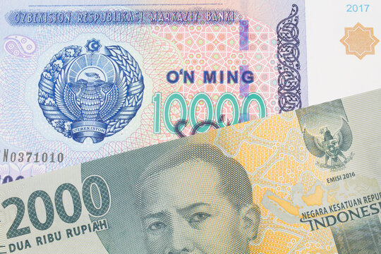 A macro image of a grey two thousand Indonesian rupiah bank note paired up with a blue, white and green ten thousand som note from Uzbekistan.  Shot close up in macro.