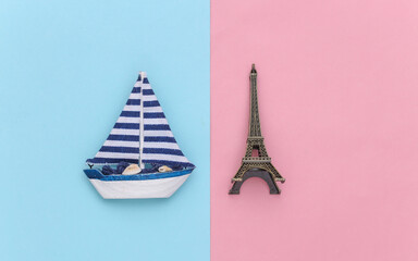 Sailboat and Eiffel Tower on a blue pink background. Minimalism travel concept. Top view. Flat lay